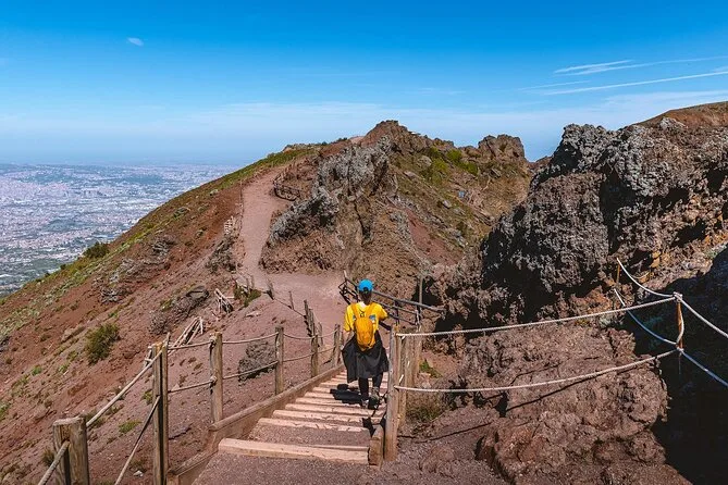 A hiker on the rim path of Vesuvius with the crater wall beside